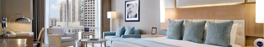 Elegant modern hotel room with city view, plush bedding, and sitting area.