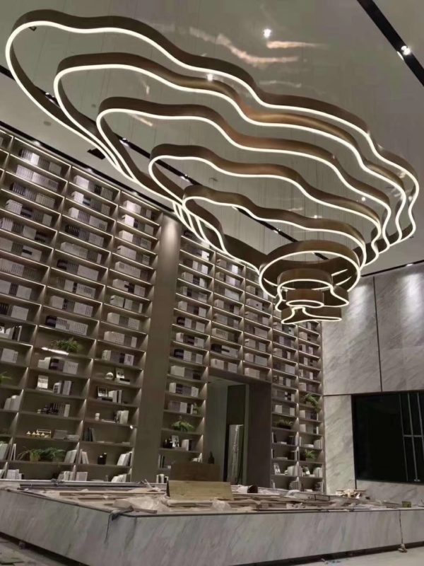 Modern library interior with artistic ceiling light design and bookshelves.