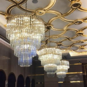 Elegant crystal chandeliers with gold accents in a luxury hotel lobby.