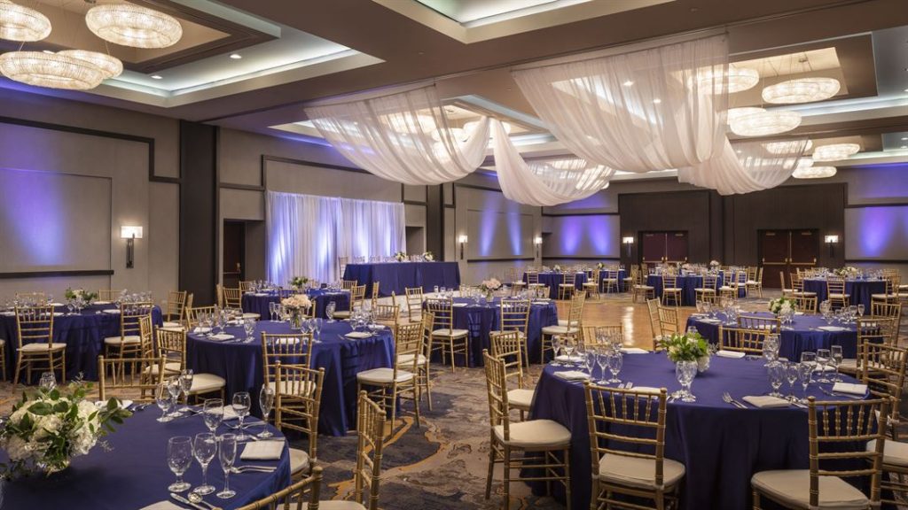 Elegant banquet hall setup with blue tablecloths and white drapery