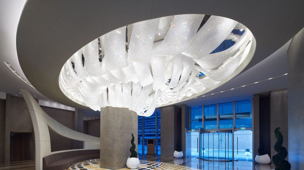 Elegant modern lobby with a large, swirling crystal chandelier centerpiece.